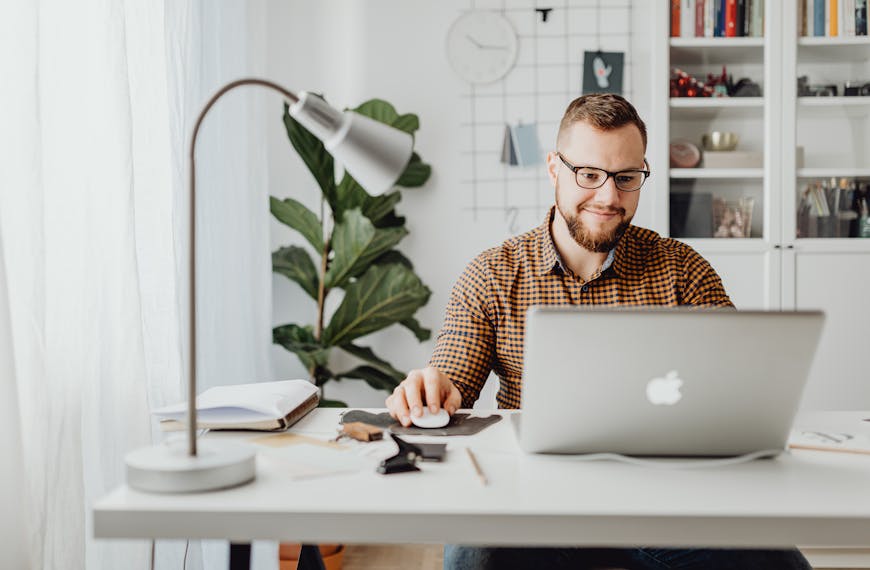 Adult male working remotely in a stylish home office with a laptop, displaying a modern workspace.