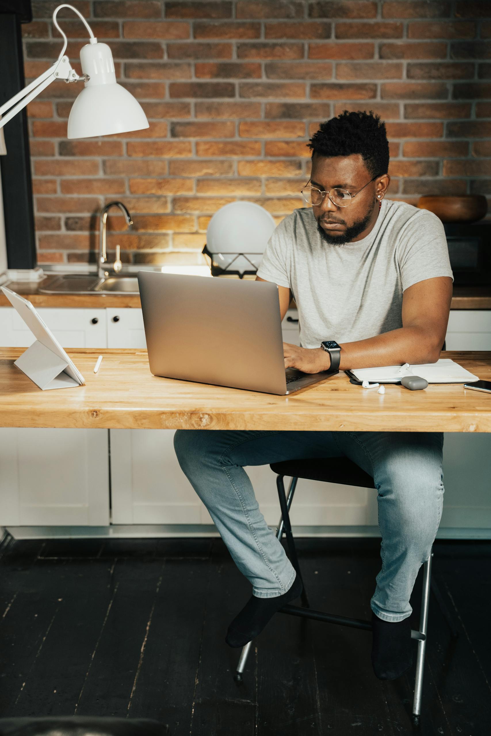 African American man working on a laptop in his home office setting, focusing on remote work tasks.