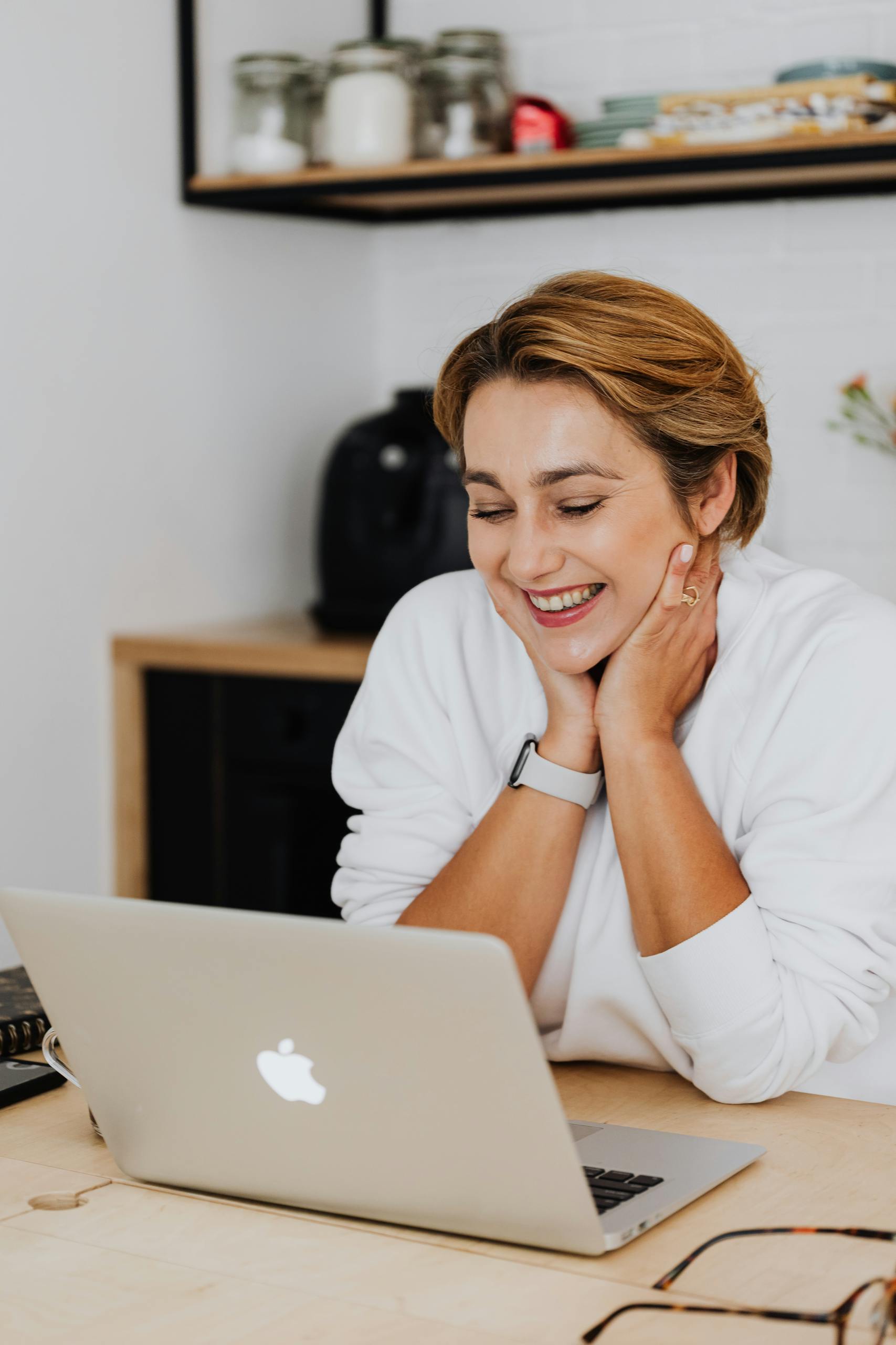 Woman smiling while using a laptop in a cozy home office setting.